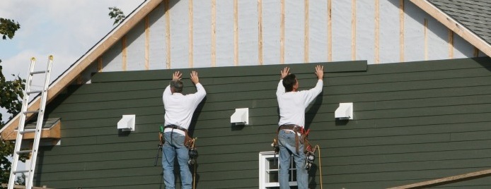 two men adding siding to a home